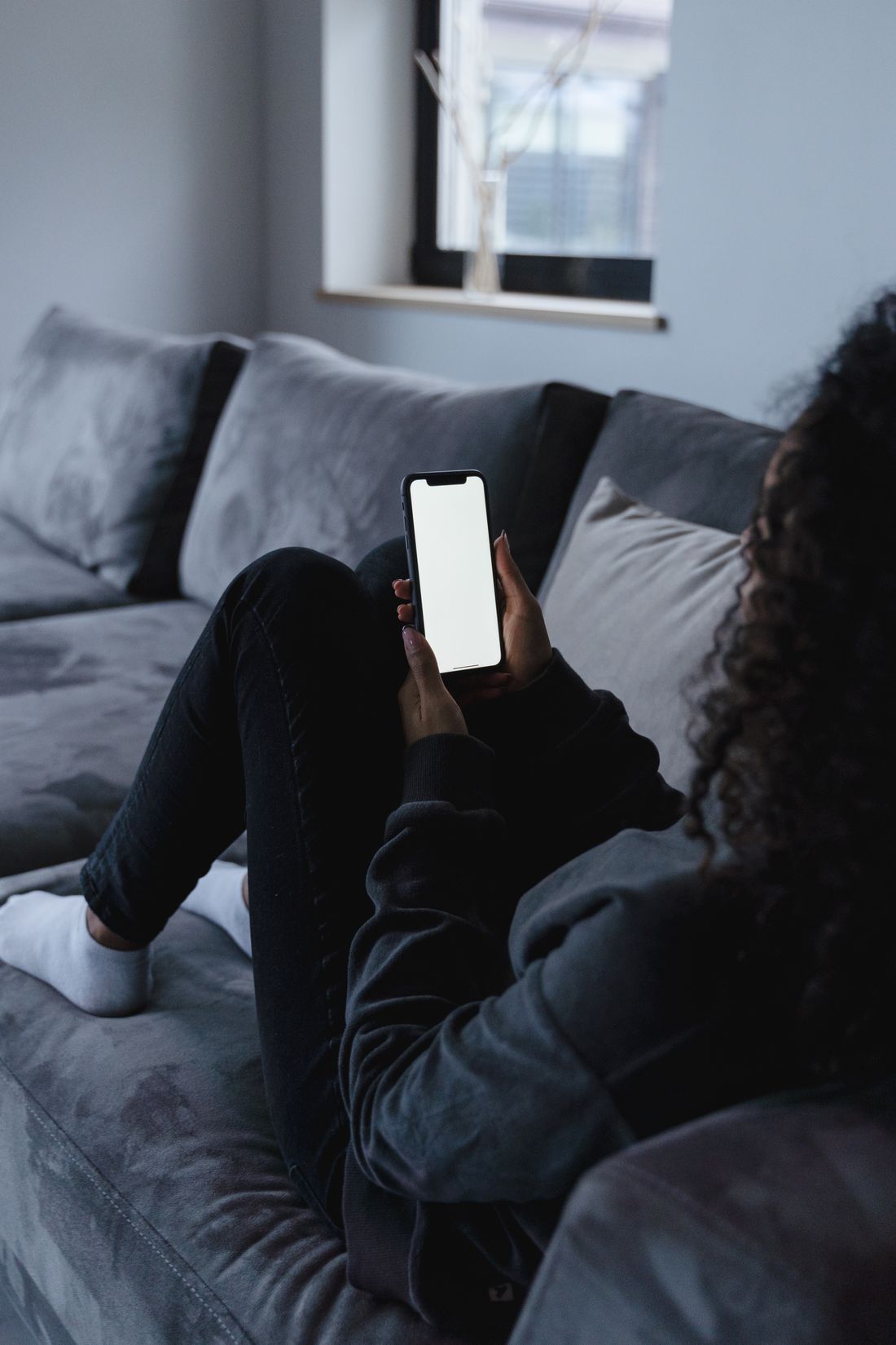 A homeowner on the couch, looking at her phone